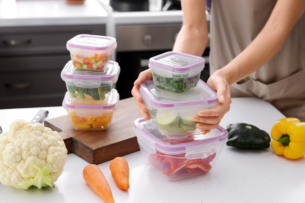 persona con contenedores de alimentos en mesa de cocina