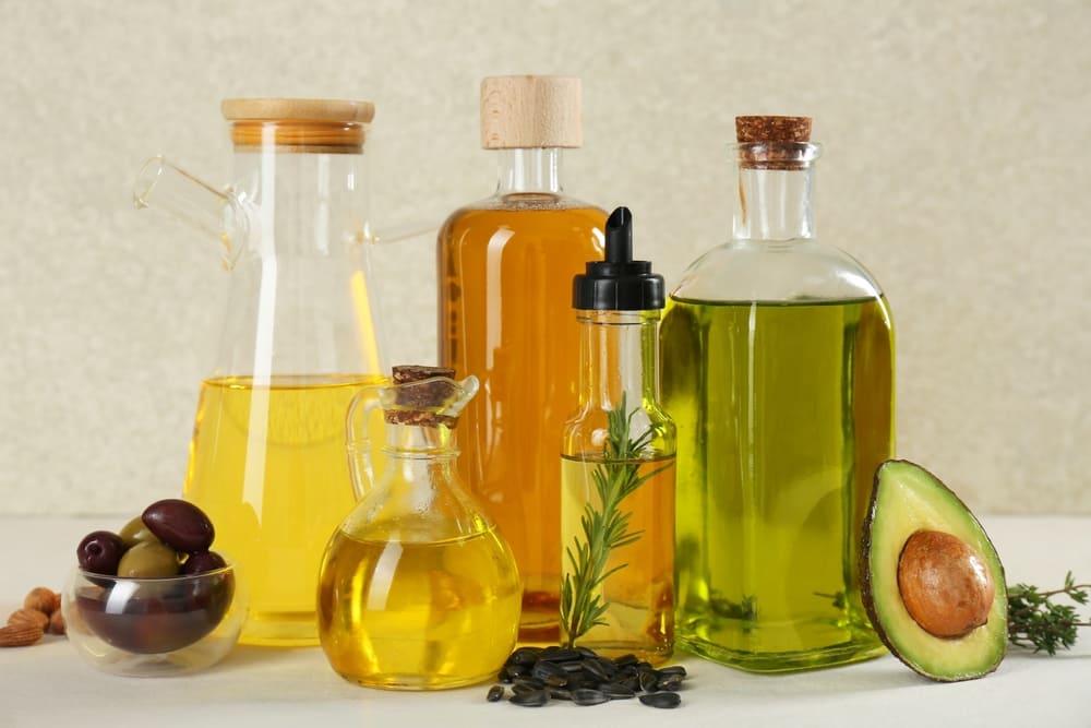 frascos de vidrio con distintos tipos de aceites sanos para cocinar: aceite de oliva, aceite de aguacate, de girasol. 