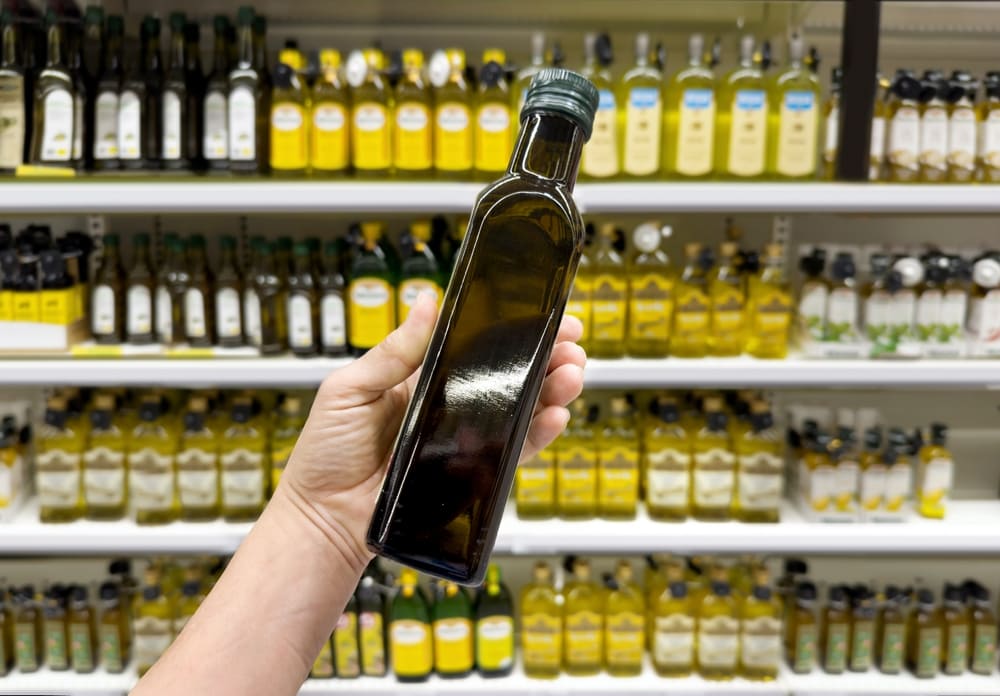 mano sosteniendo botella de aceite de oliva extra virgen en supermercado
